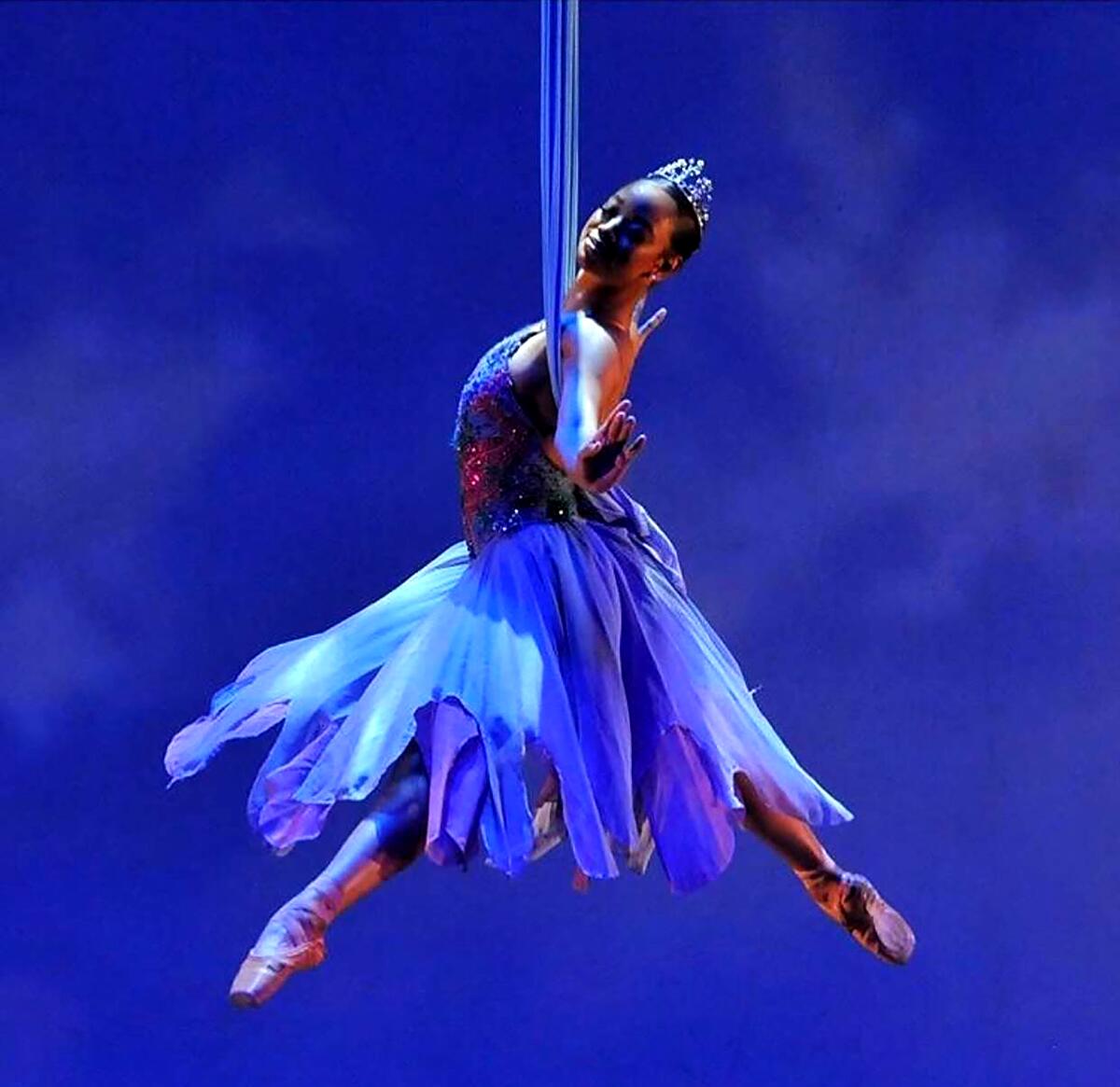 A ballerina hanging from a silk rope with her legs and arms stretched out