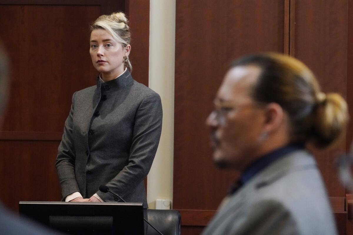 FILE - Actors Amber Heard and Johnny Depp watch as the jury leaves the courtroom for a lunch break at the Fairfax County Circuit Courthouse in Fairfax, Va., Monday, May 16, 2022. A new court filing on Friday, July 8, 2022, from Heard's legal team, alleges one of the jurors in the defamation case filed against her by her ex-husband Depp served improperly. (AP Photo/Steve Helber, Pool, File)