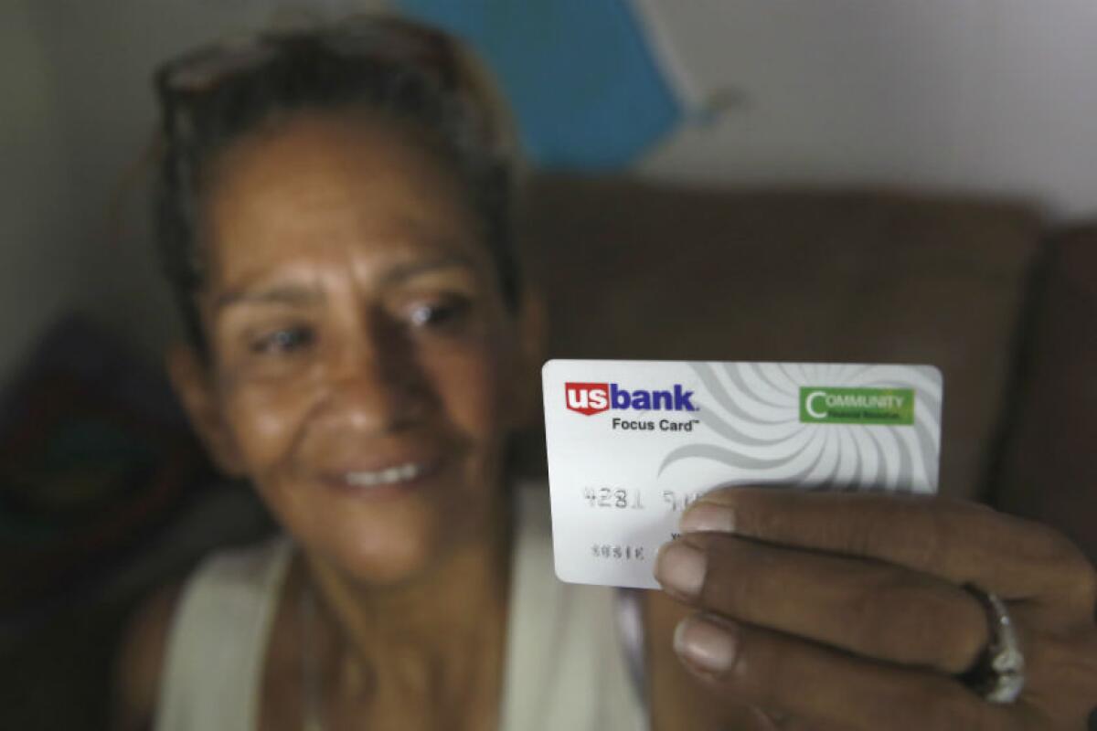 Susie Garza displays a city-provided debit card she receives monthly through a trial program in Stockton.  She  is part of an experiment testing the impact of "universal basic income."