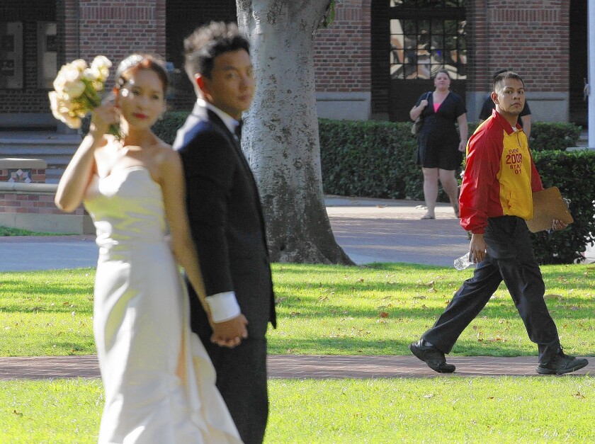 A USC security "ambassador" patrols at right as Alex Park and Jiin Kim are photographed on the eve of their wedding.