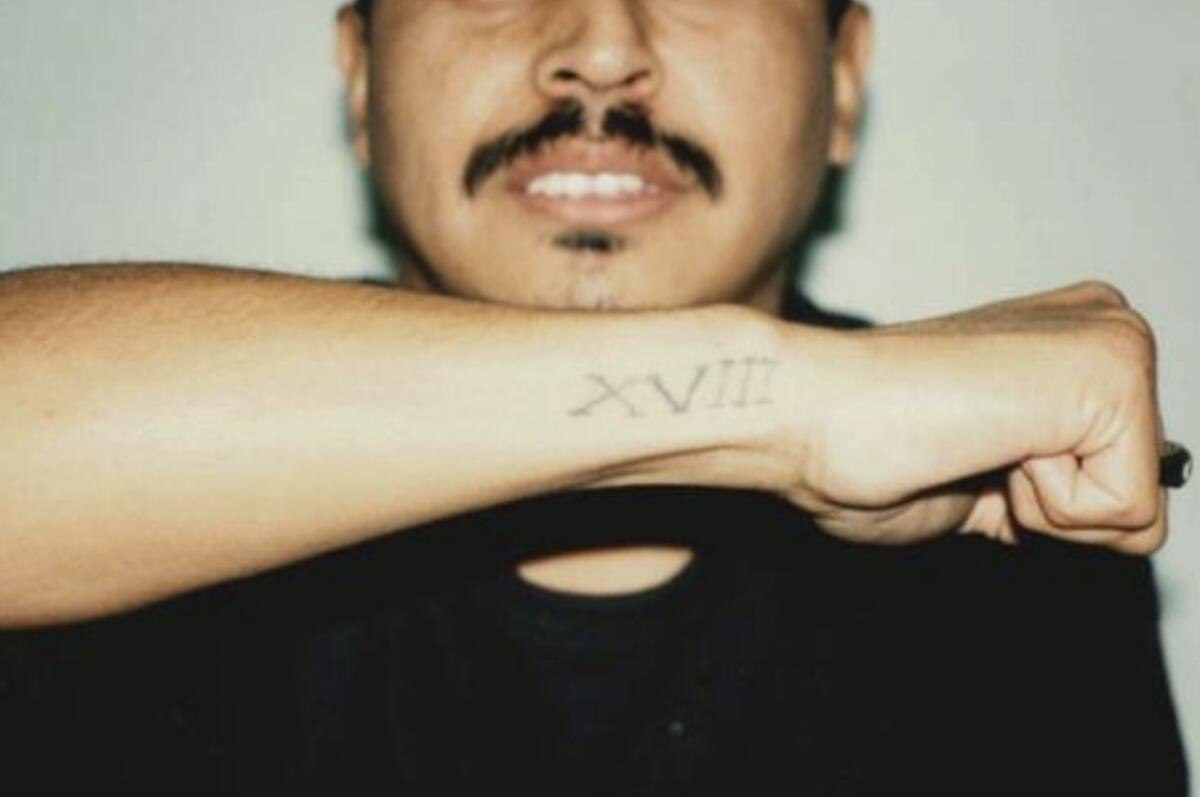 Juan Romero, shown here displaying his 18th Street tattoo, is charged with 12 counts of murder.
