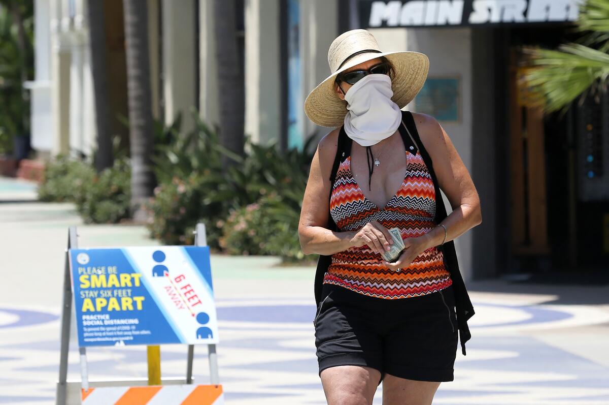 Rachel Stern walks while wearing a face cover near the Balboa Fun Zone on Monday.