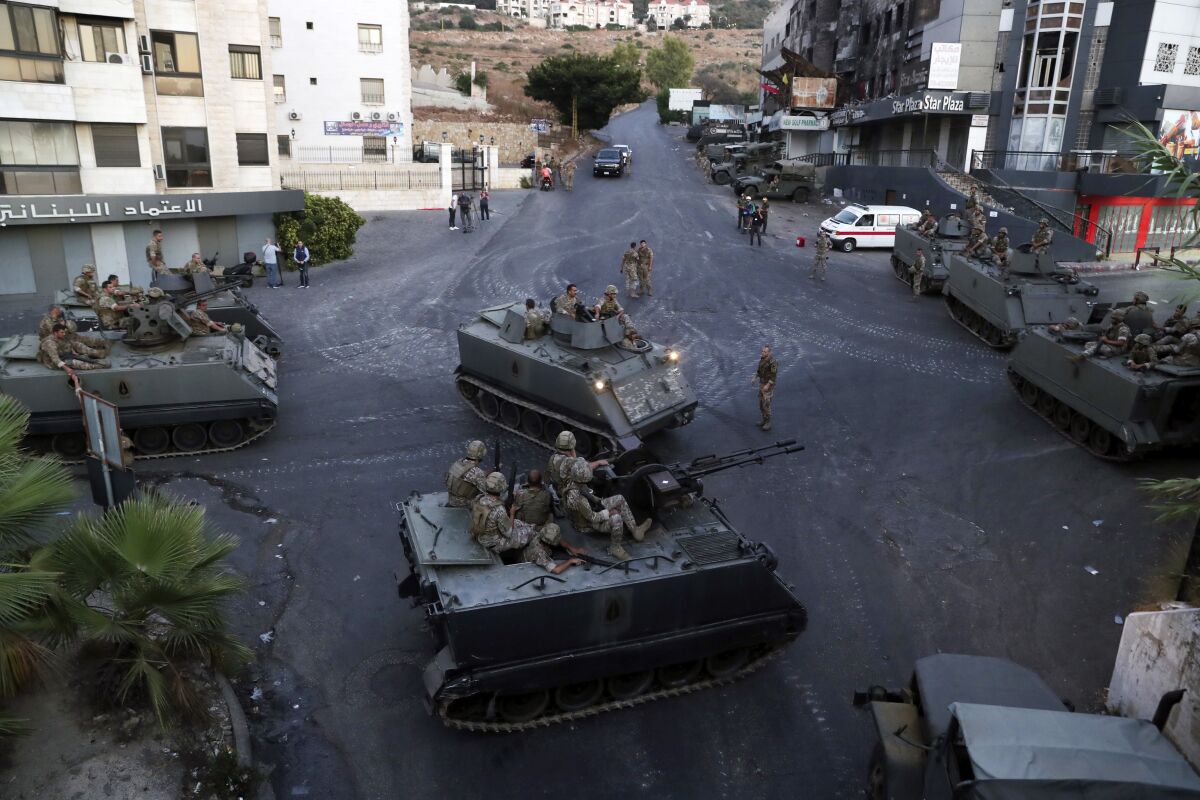 Lebanese army soldiers sit on their armored vehicles as they deployed to contain the tension after heavy fire in the coastal town of Khaldeh, south of Beirut, Lebanon, Sunday, Aug. 1, 2021. At least two people were killed on Sunday south of the Lebanese capital when gunmen opened fire at the funeral of a Hezbollah commander who was killed a day earlier, an official from the group said. (AP Photo/Bilal Hussein)