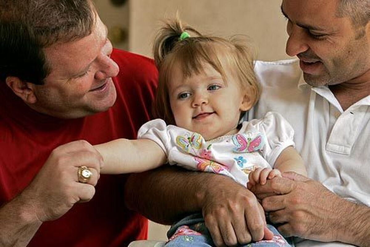 Rick Karl, left, and Bruce Steiger play with their daughter, Krystie. When Karl and Steiger decided to have a child, they hired a surrogate and used a donor egg. Krystie was born with Tay-Sachs.