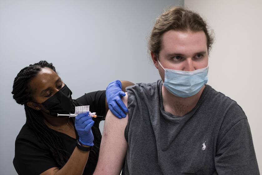 Cole Smith receives a Moderna variant vaccine shot from clinical research nurse Tigisty Girmay at Emory University's Hope Clinic, on Wednesday afternoon, March 31, 2021, in Decatur, Ga. Smith, who received Moderna's original vaccine a year ago in a first-stage study, said returning wasn’t a tough decision. “The earlier one, it was a great success and, you know, millions of people are getting vaccinated now. ... If we’re helping people with the old one, why not volunteer and help people with the new one?” (AP Photo/Ben Gray)