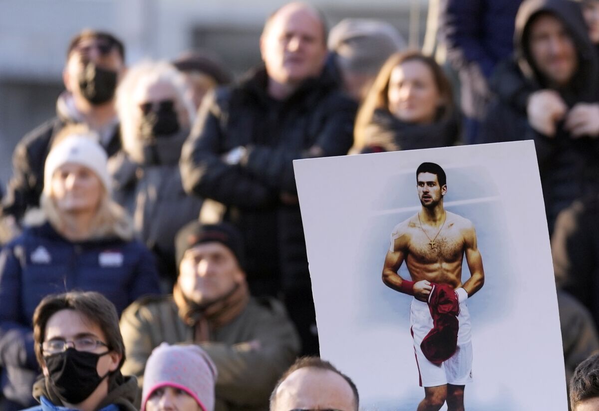 Supporters of Novak Djokovic protest, with one holding an image of him