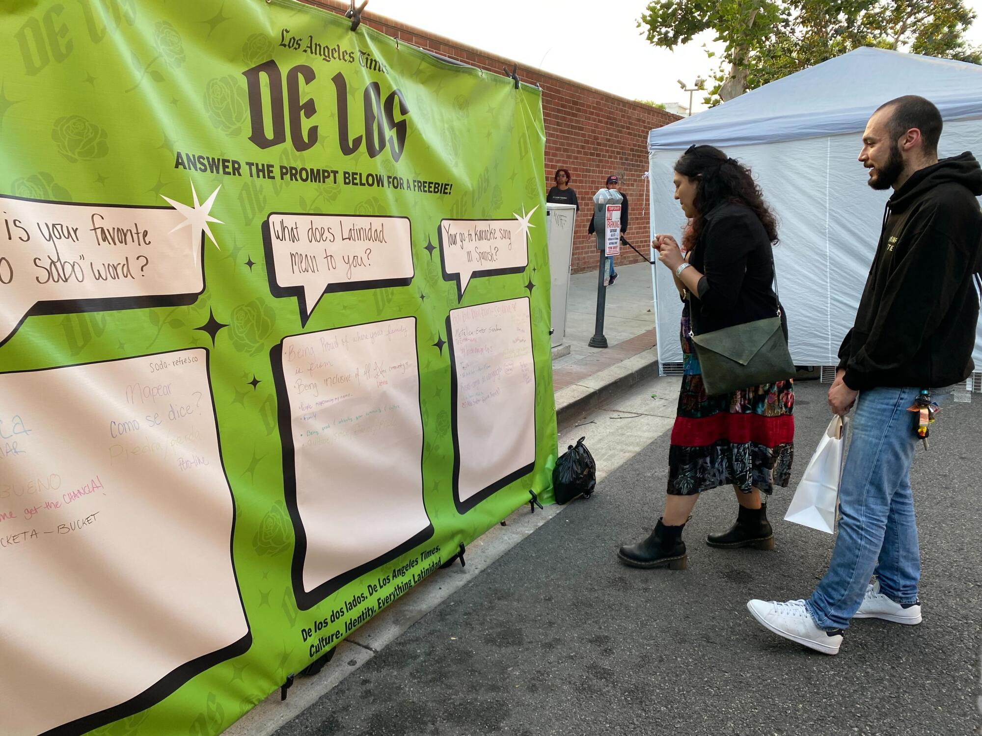 Guests write on a vinyl banner at a De Los booth