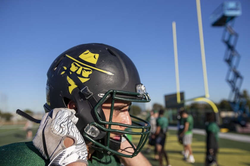 Marcus Schlabitz, a safety for the Golden West College football team, straps on his helmet during practice on Thursday.