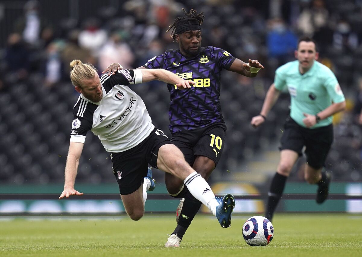 Fulham's Tim Ream, left, and Newcastle United's Allan Saint-Maximin battle for the ball during the English Premier League soccer match at Craven Cottage, London, Sunday May 23, 2021. (Matthew Childs/Pool via AP)