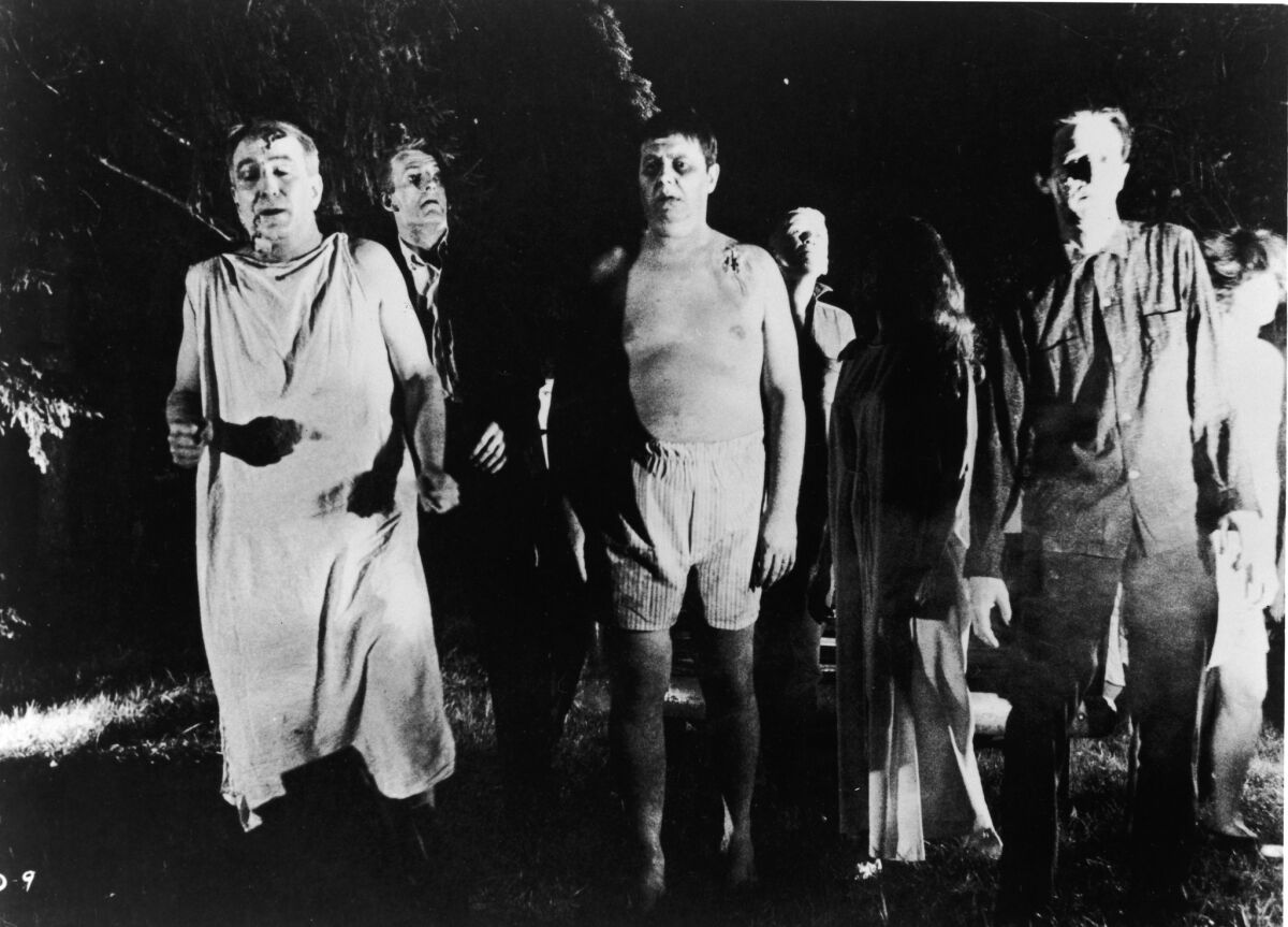 “Zombies” walk through a field in the night in a still from the film  “Night Of The Living Dead.”