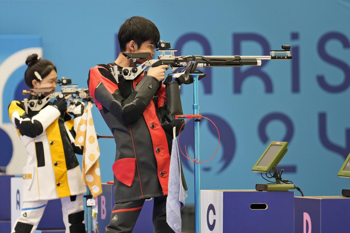 China's Sheng Lihao, right, and teammate Huang Yuting compete for the gold medal in mixed 10-meter air rifle.