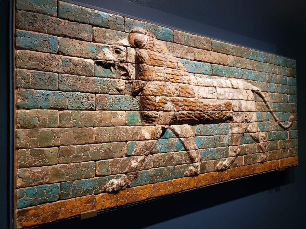 A striding lion is depicted in bas-relief on glazed ceramic tiles.