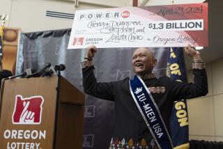 Cheng "Charlie" Saephan sostiene un cheque gigante por valor de 1.300 millones de dólares sobre su cabeza durante una conferencia de prensa donde se dio a conocer que era uno de los ganadores de la lotería de Powerball, en Salem, Oregon, el lunes 29 de abril de 2024. (AP Foto/Jenny Kane)