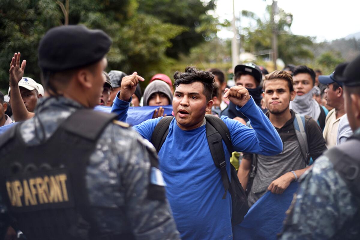 Honduran migrants are met by Guatemalan police officers after crossing the border near Esquipulas, Guatemala, on Thursday.