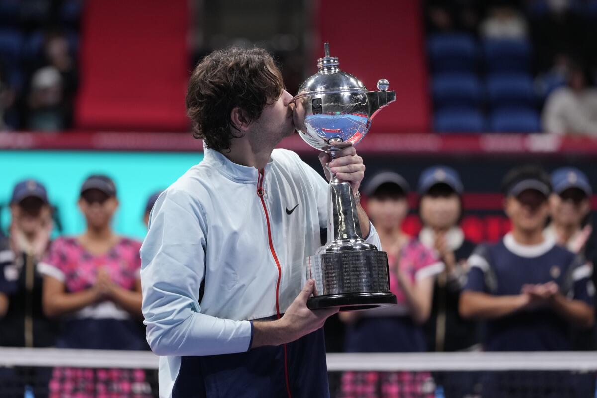 Taylor Fritz of the U.S. kisses his champion trophy during the award ceremony for the singles of the Japan Open tennis championships in Tokyo, Sunday, Oct. 9, 2022. (AP Photo/Hiro Komae)
