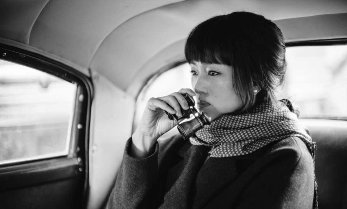 A woman in the backseat of a car holding binoculars in the movie “Saturday Fiction.”