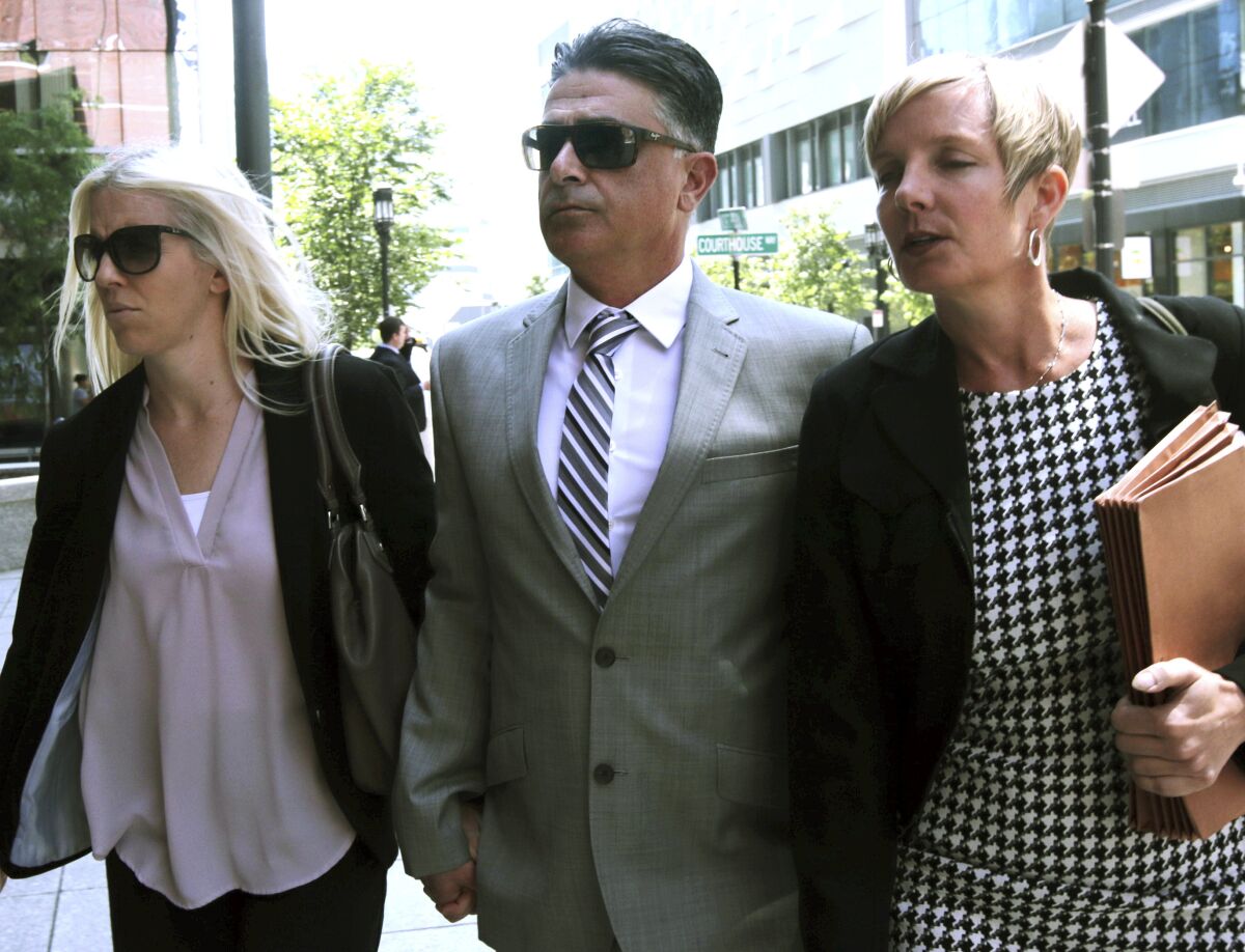 Former USC women's soccer coach Ali Khosroshahin arrives at a federal court flanked by two women