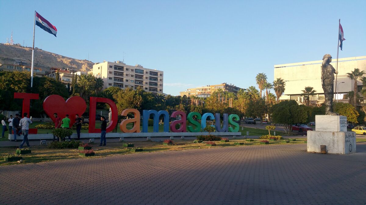 Pedestrians lounge near the newly installed "I love Damascus" sign in Damascus, Syria, on Oct. 31.