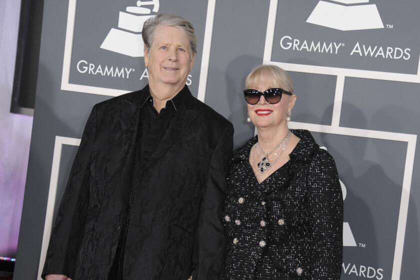 Brian Wilson and Melinda Wilson, both dressed in black, holding hands as they arrive at the 2013 Grammys
