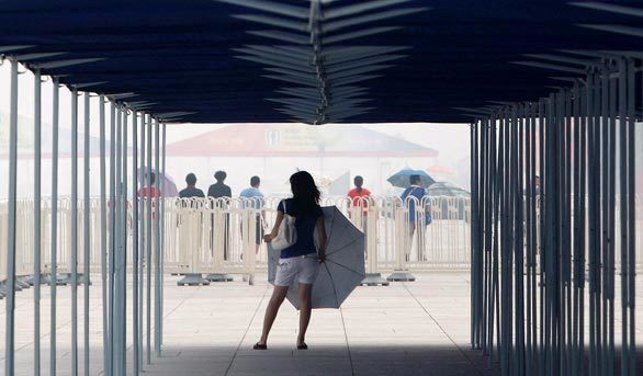 A Chinese girl with a parasol waits outside the National Stadium at the Beijing 2008 Olympics in hazy and humid weather.