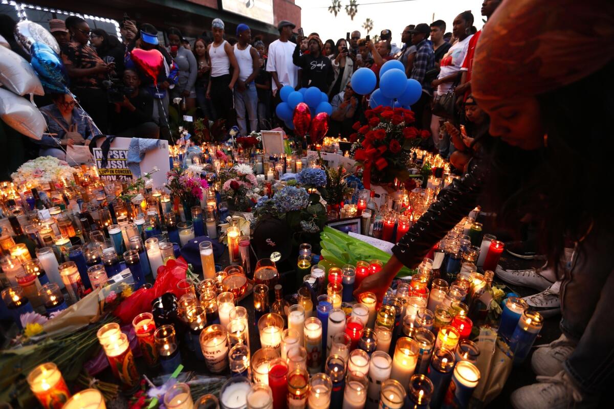 Fans of rapper Nipsey Hussle pay their respects at a memorial in the parking lot of the Marathon Clothing store in South Los Angeles. (Genaro Molina / Los Angeles Times)