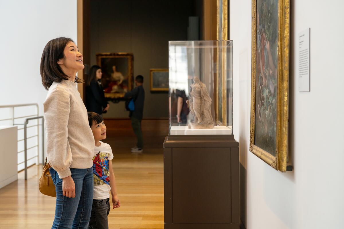 A woman and a child look at a painting.