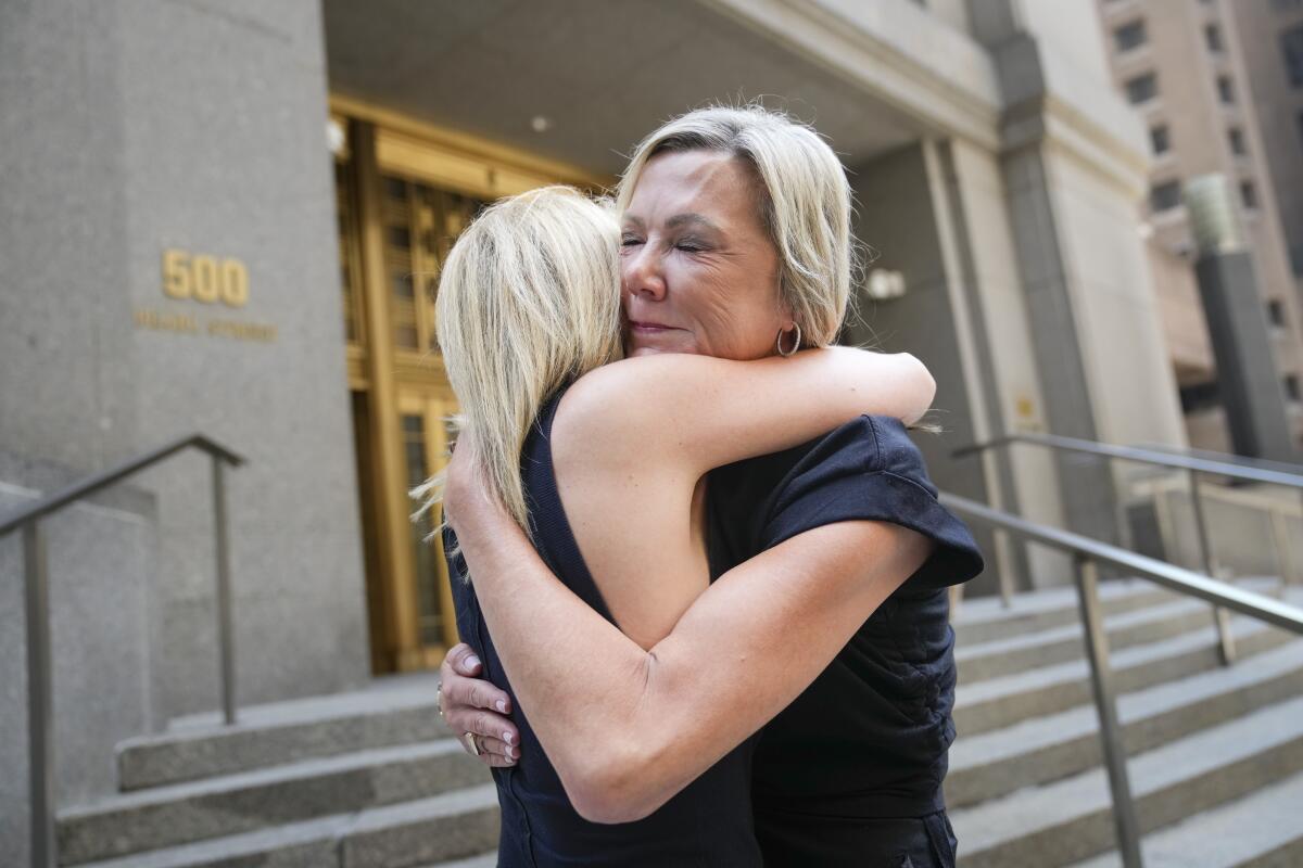 Two women embrace outside a courthouse.