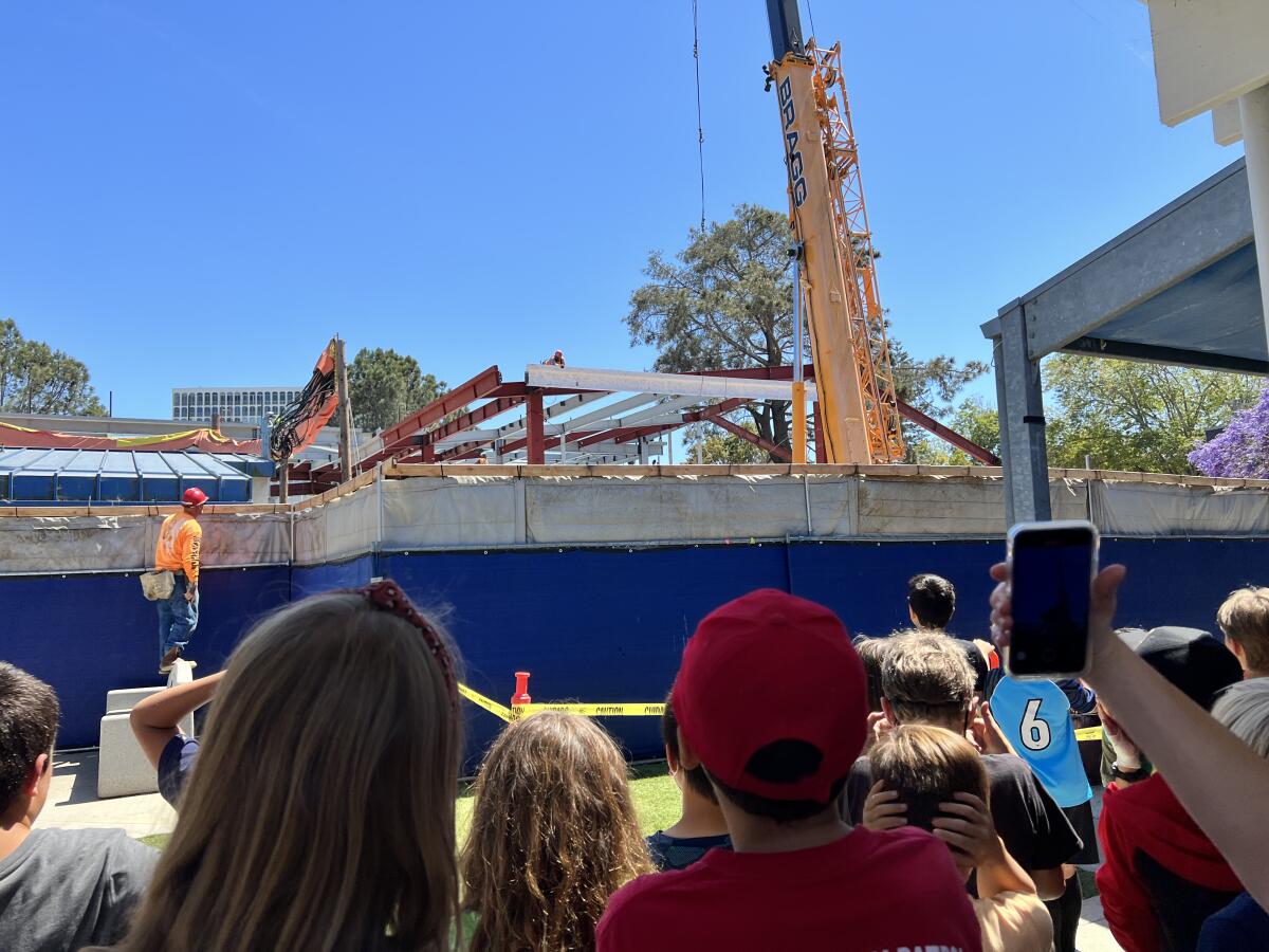 Workers hoist a white beam bearing signatures to the top of a new structure at La Jolla Elementary School on May 13.