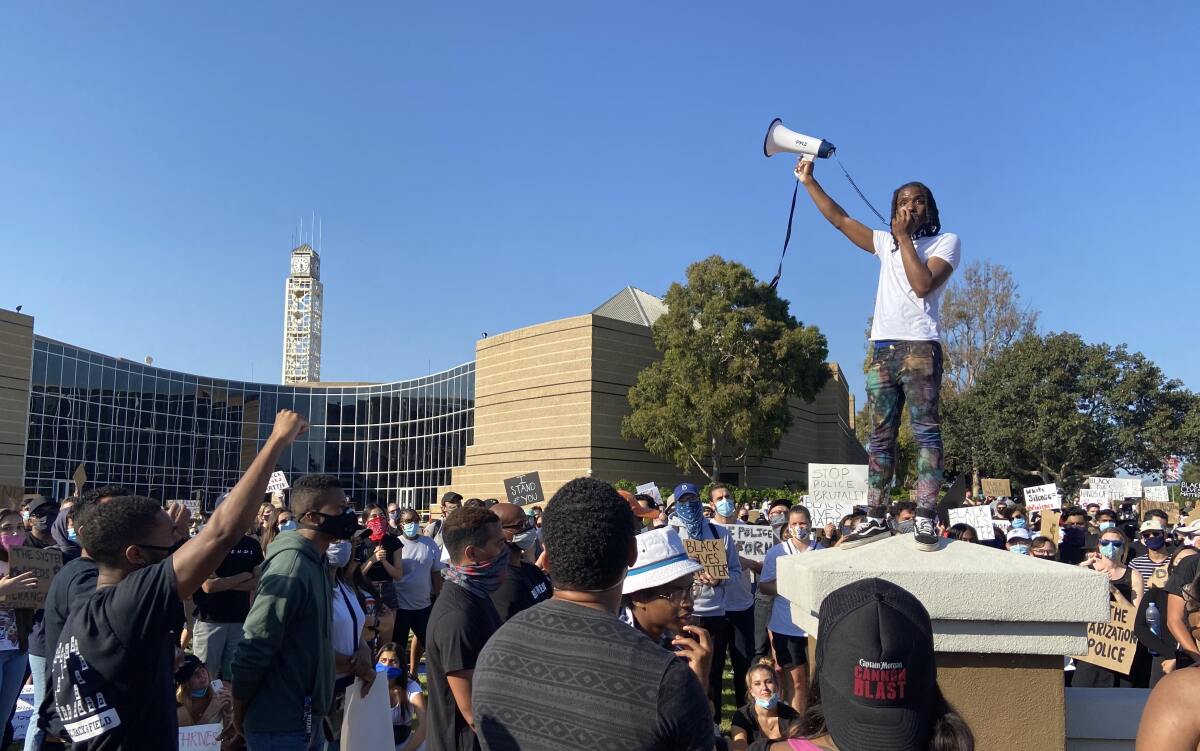 Khalil Mcleod stands atop a pillar outside Irvine City Hall during a protest Wednesday.
