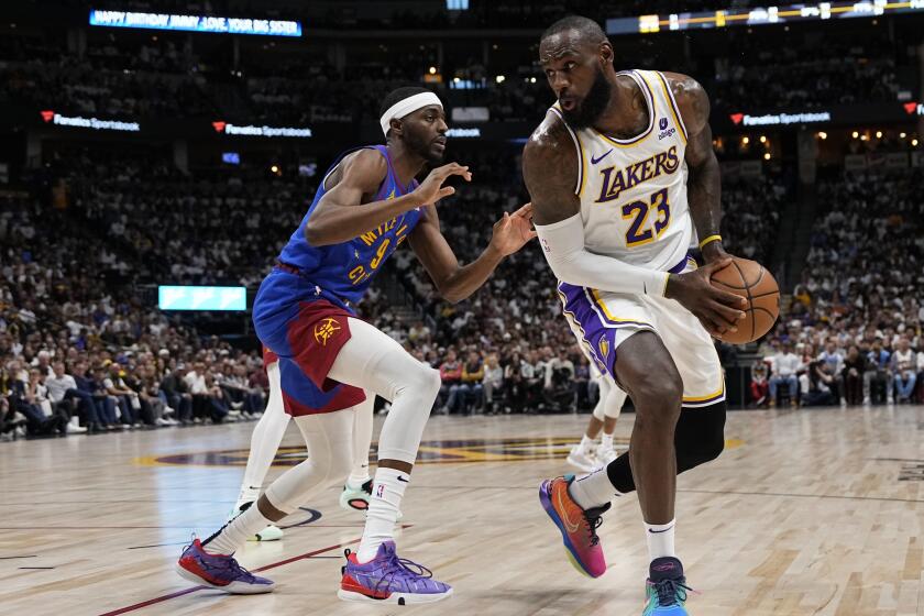 Los Angeles Lakers forward LeBron James (23) is pressured by Denver Nuggets forward Justin Holiday.