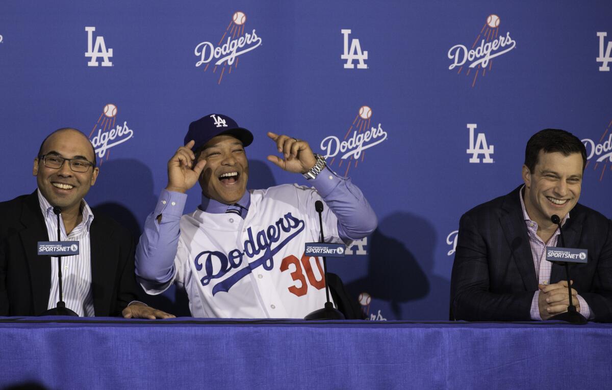 New Dodgers Manager Dave Roberts (30) shares a laugh on stage with General Manager Farhan Zaidi, left, and President of Baseball Operations Andrew Friedman, right, during an introductory news conference.