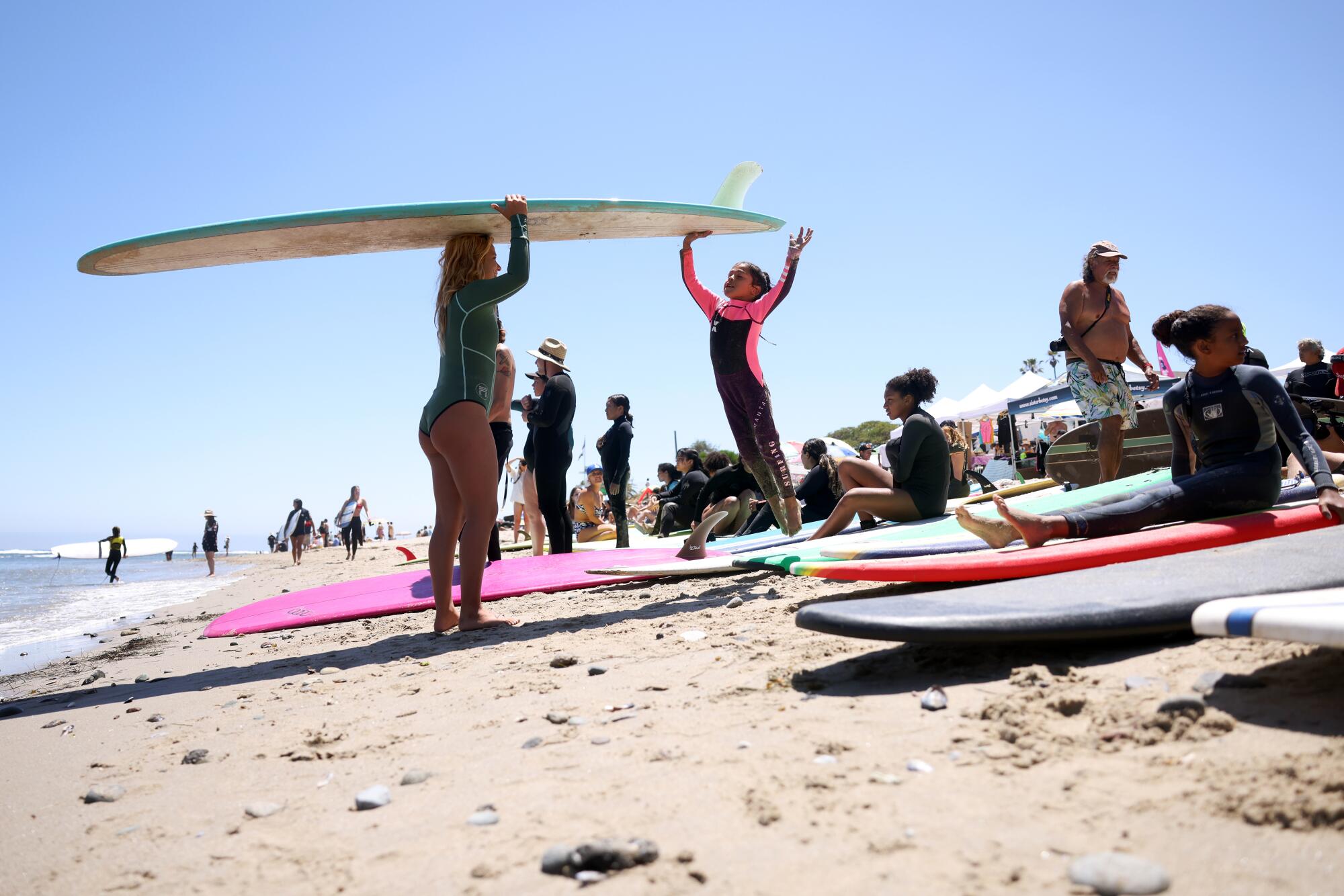 Dahlia Castaneda jumps up to touch a board just before getting in the water for a surf lesson at First Point in Malibu.