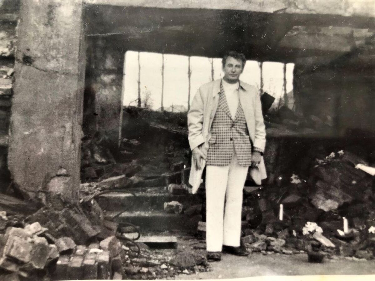 Mel Mermelstein stands in the wreckage of a former concentration camp
