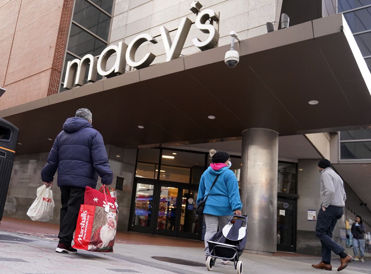 FILE - Shoppers walk to the Macy's store in the Downtown Crossing district, Wednesday, Nov. 17, 2021, in Boston. Macy’s profit and sales for the holiday quarter slid with inflation leading some customers to pull back, but it beat Wall Street expectations, Thursday, March 2, 2023, and its outlook for 2023 didn’t disappoint given the uncertain economic environment. (AP Photo/Charles Krupa, File)