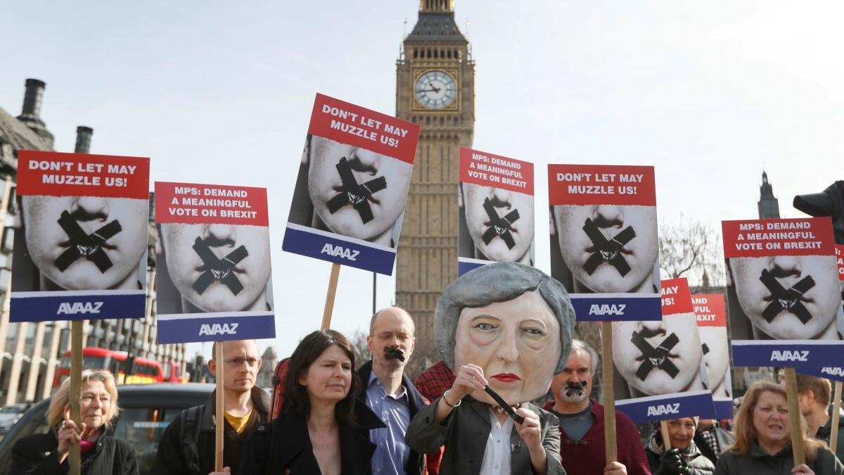 Demonstrators, one dressed in a Theresa May puppet head, pose near Parliament in London on Monday.