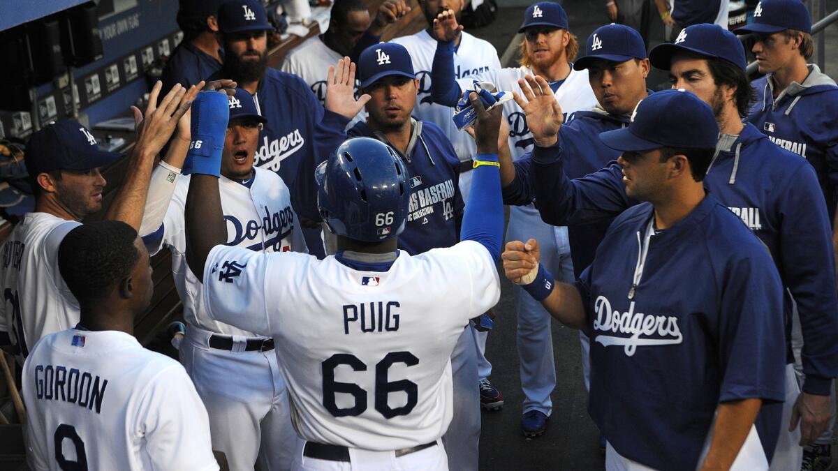 Dodgers center fielder Yasiel Puig is congratulated by his teammates after scoring against the Atlanta Braves on July 31. Strife in the clubhouse doesn't matter as long as the Dodgers are winning.