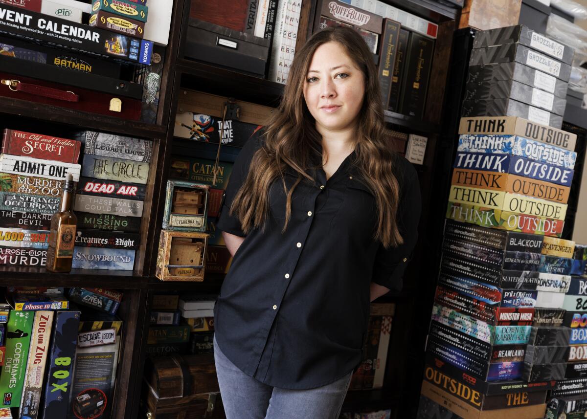 Lauren Bello stands among shelves and stacks of board games