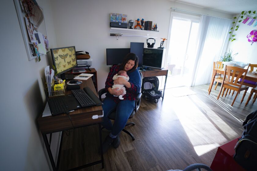 Chula Vista, CA - December 14: At at the family apartment in Chula Vista, CA., Zaira Reynoso juggles with her with two-week old baby, Ander Reynoso and checking email. Reynoso who works as a coach to family child care providers, spends a lot of day in online meetings and answering emails. Because the cost of daycare, Reynoso is working from home and caring for her baby. (Nelvin C. Cepeda / The San Diego Union-Tribune)