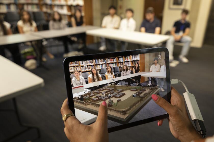 An educator uses a iPad to project a new App to student summer interns at the Museum in Los Angeles.