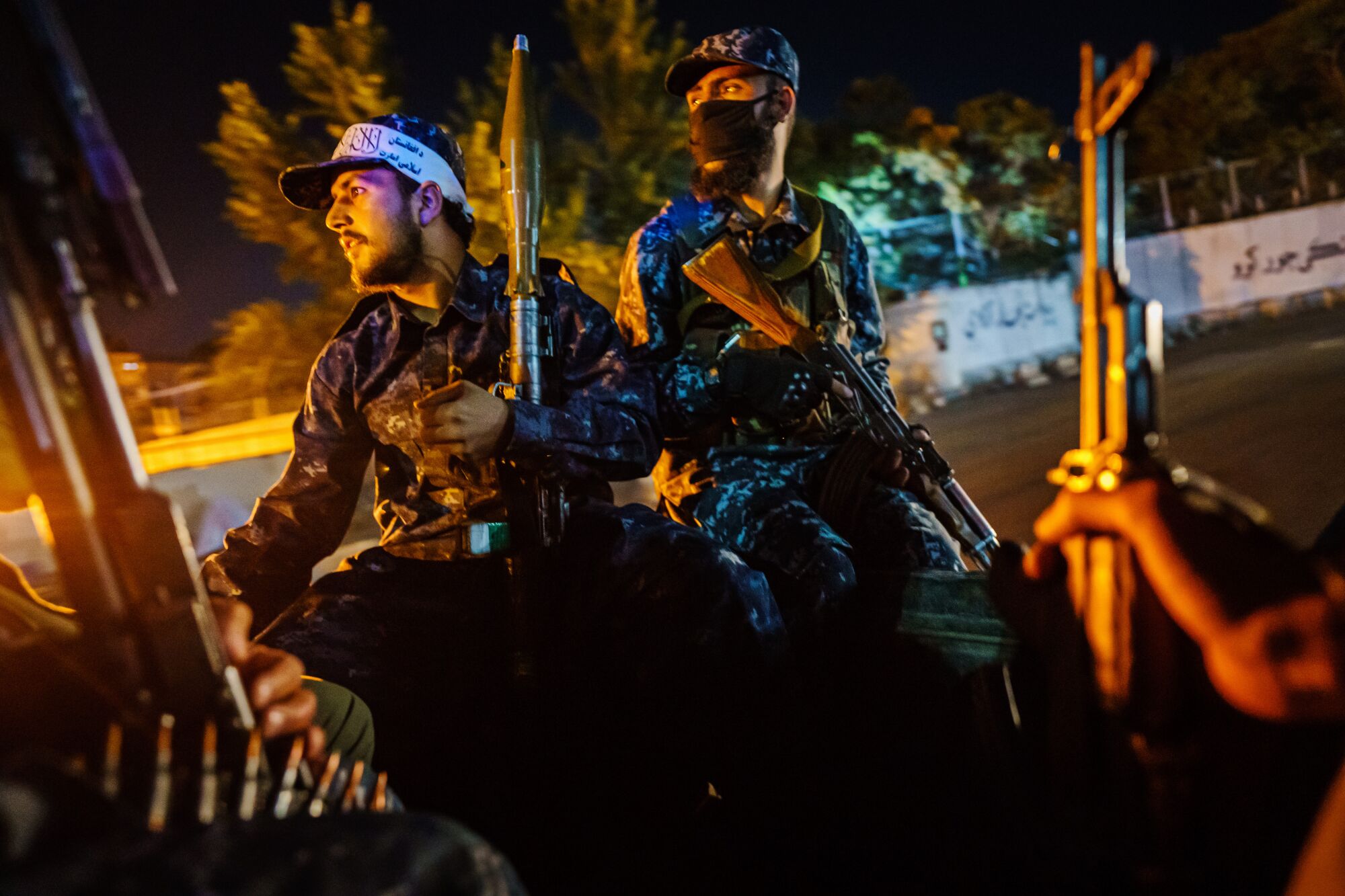 Men with rifles ride in a vehicle at night