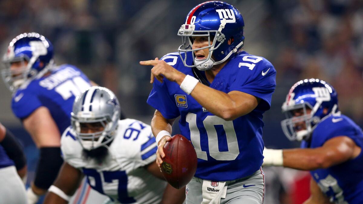 Giants quarterback Eli Manning looks downfield as he scrambles from the pressure of the Cowboys' pass rush on Sunday.