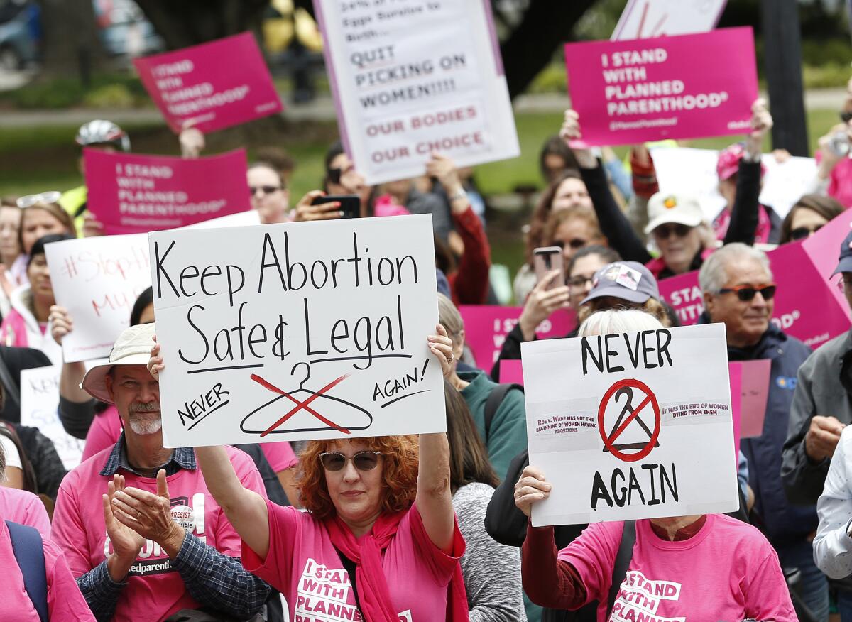 People in pink shirts hold signs in support of abortion rights at a rally outside the state Capitol in Sacramento 