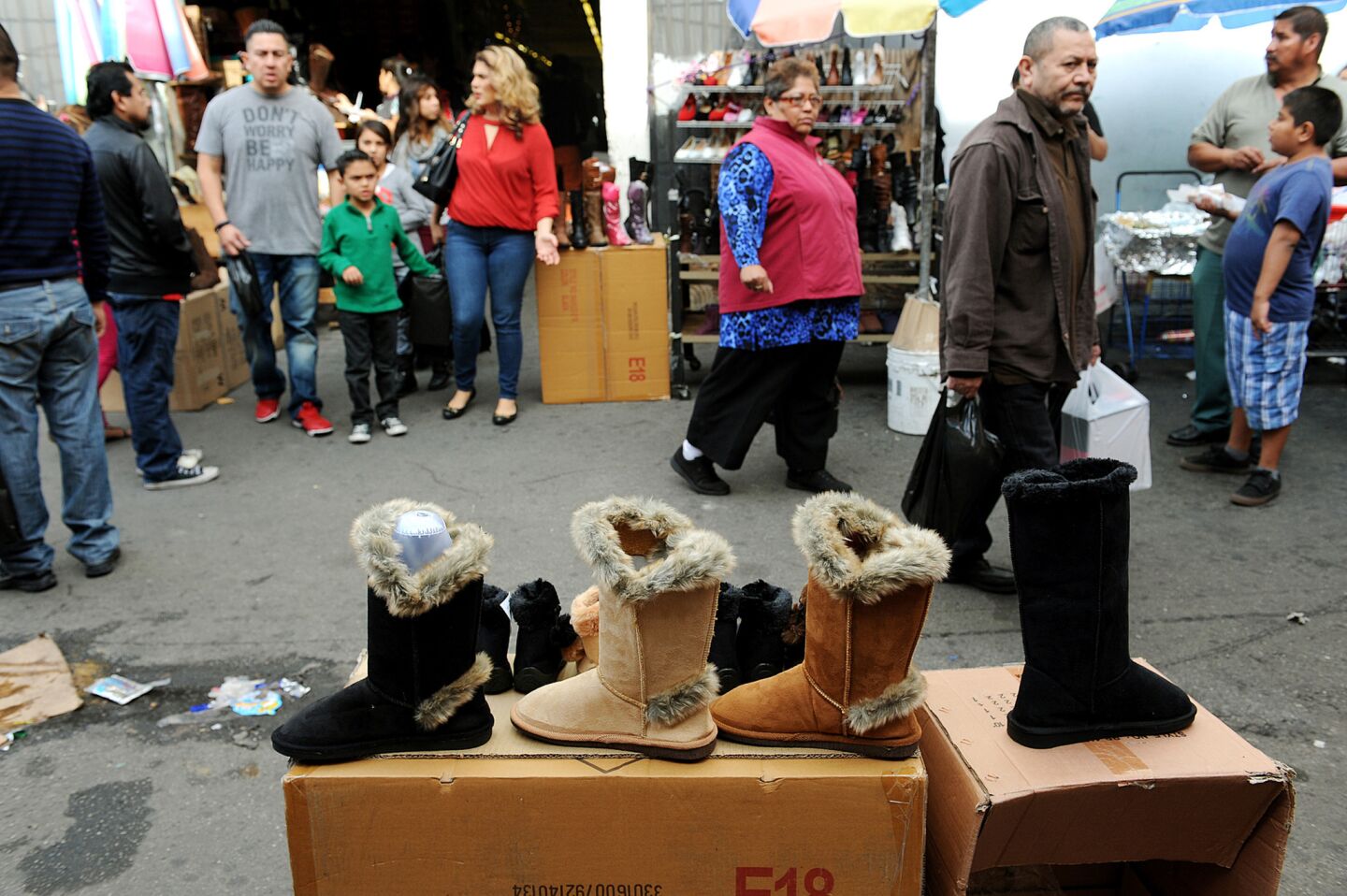 Downtown shoppers pass by boots on display. As more shoppers head downtown for bargains, more street vendors show up to offer them food and drink.