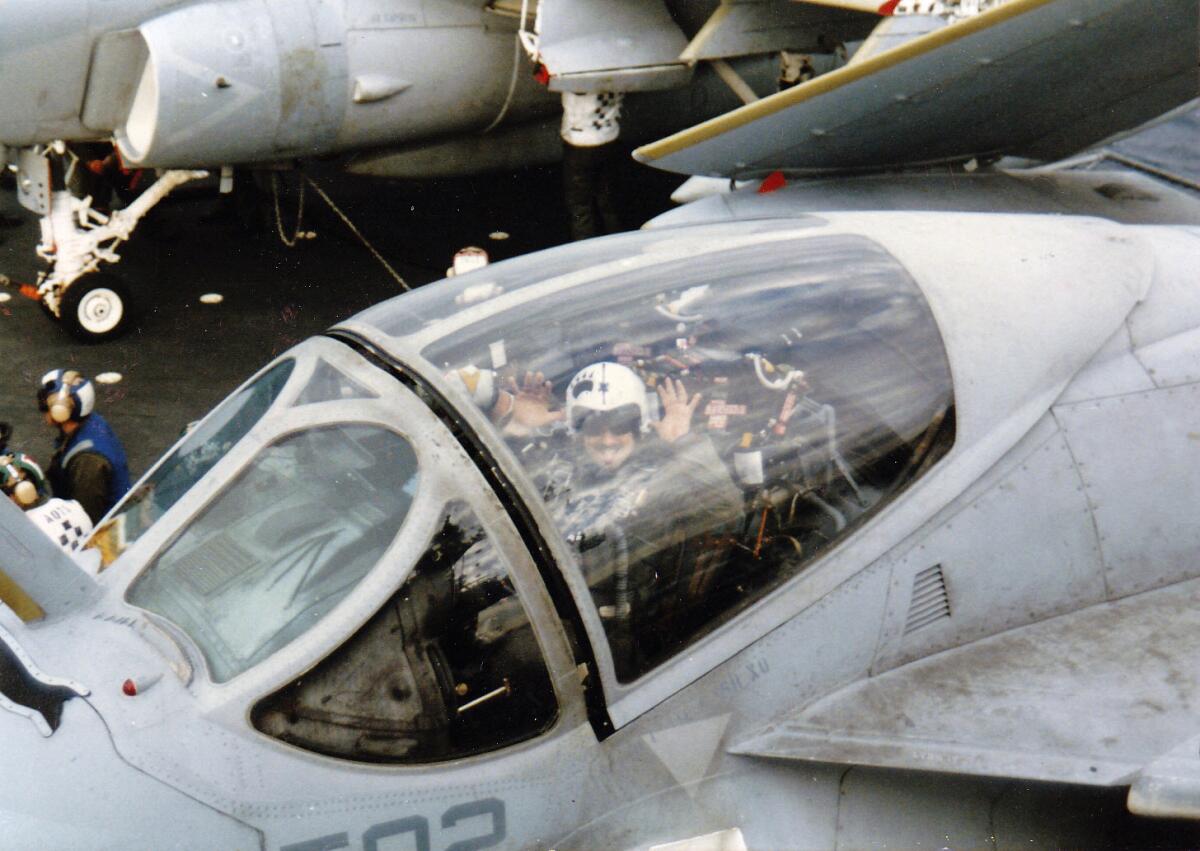 Navy A-6 Intruder pilot Jim Seaman holds up his hands in the cockpit of a military plane. 