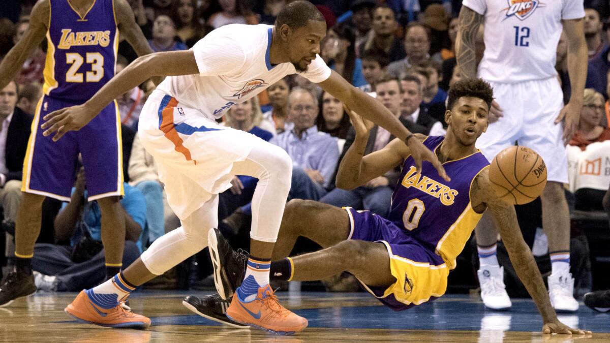 Thunder forward Kevin Durant tracks down a loose ball next to Lakers forward Nick Young (0) during their game Saturday.