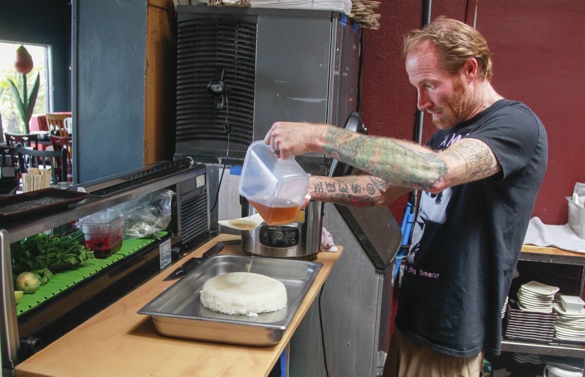 Chef Davin Waite pours sushi-zu (a sushi rice seasoning solution) over rice at his restaurant.