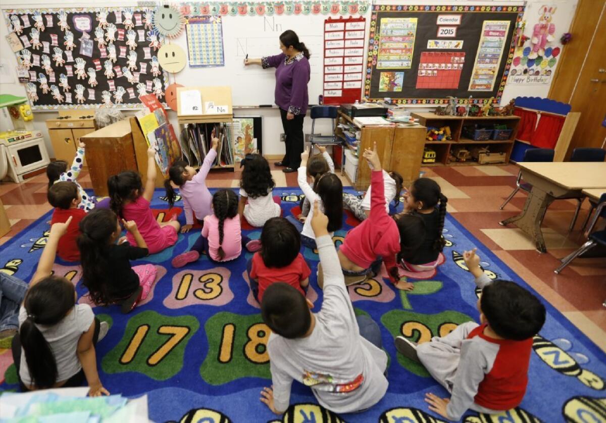 Students raise their hands in a pre-kindergarten classroom.