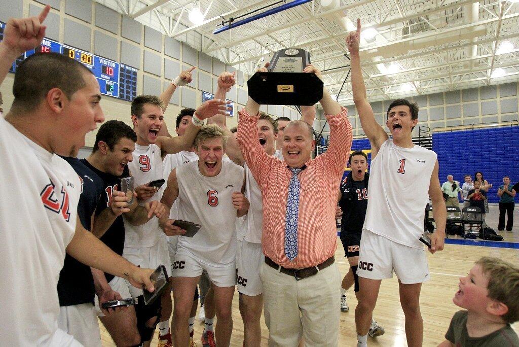 Orange Coast College head coach Travis Turner holds up the championship trophy as the Pirates celebrate beating Santa Monica in the 2014 California Community College Athletic Assn. State Championship match.