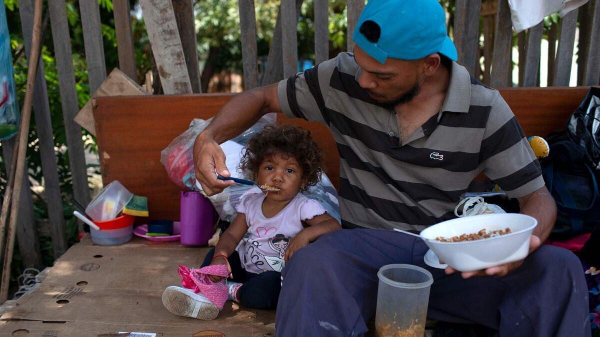 A Venezuelan man and his daughter eat a meal on the side of a road in Boa Vista, Roraima state, Brazil.