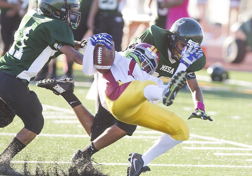 Estancia's Kevin Sanchez is wrapped up and taken down by a Costa Mesa tackler.